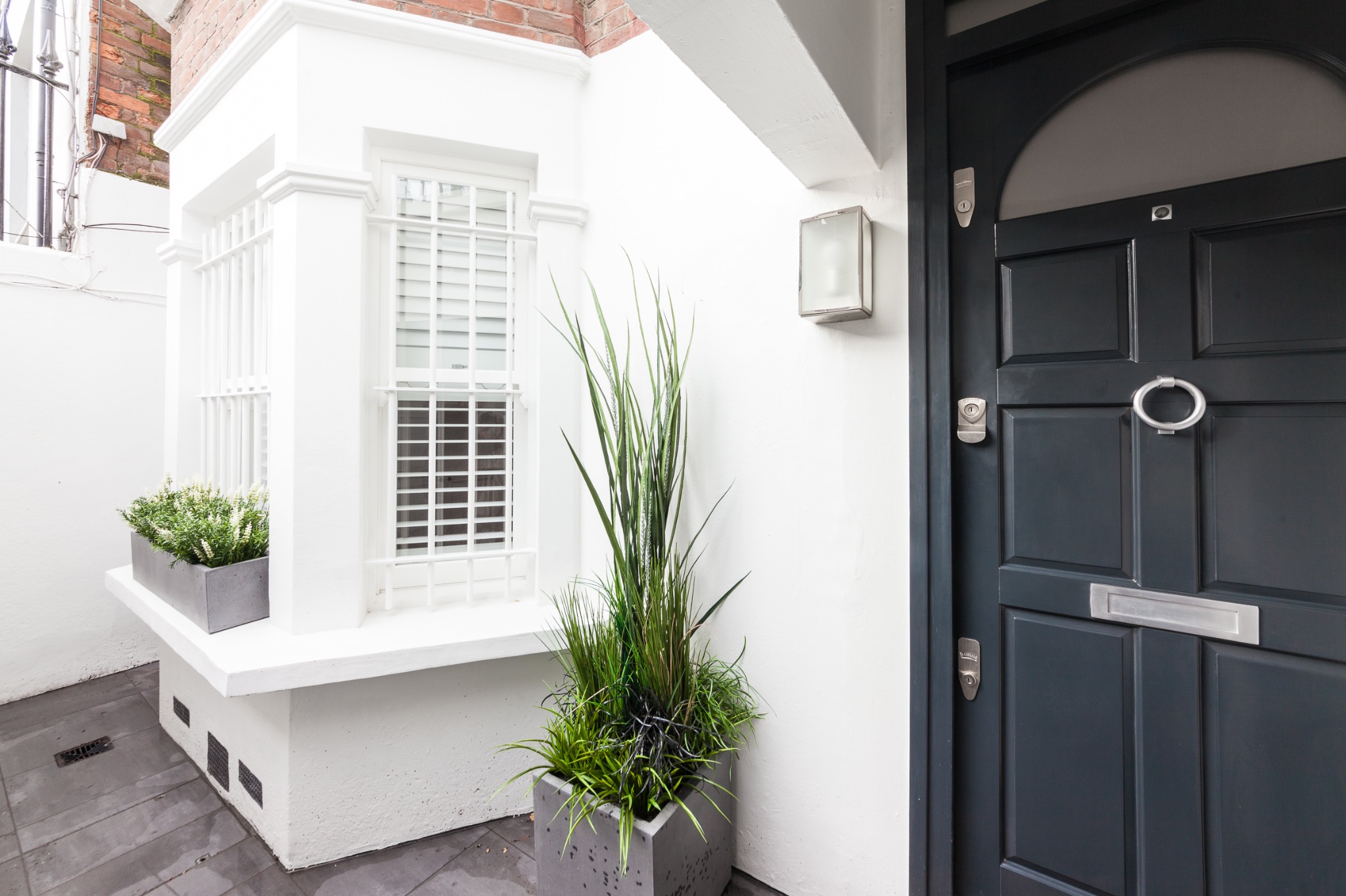 Chelsea entrance with black front door and white plantation shutters