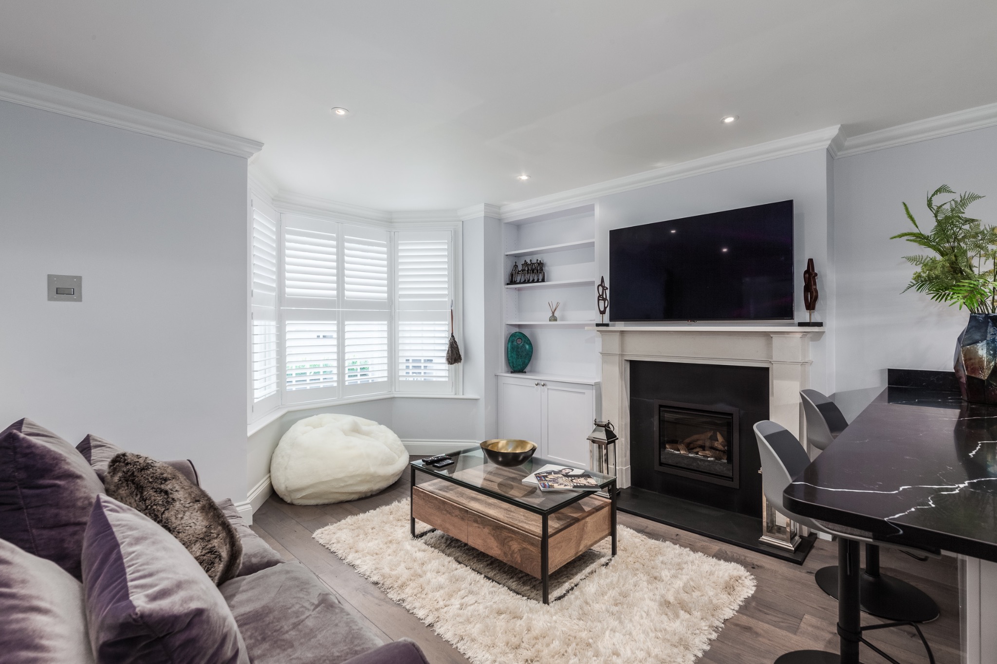 Chelsea living room with bespoke white plantation shutters, integrated shelving and fireplace