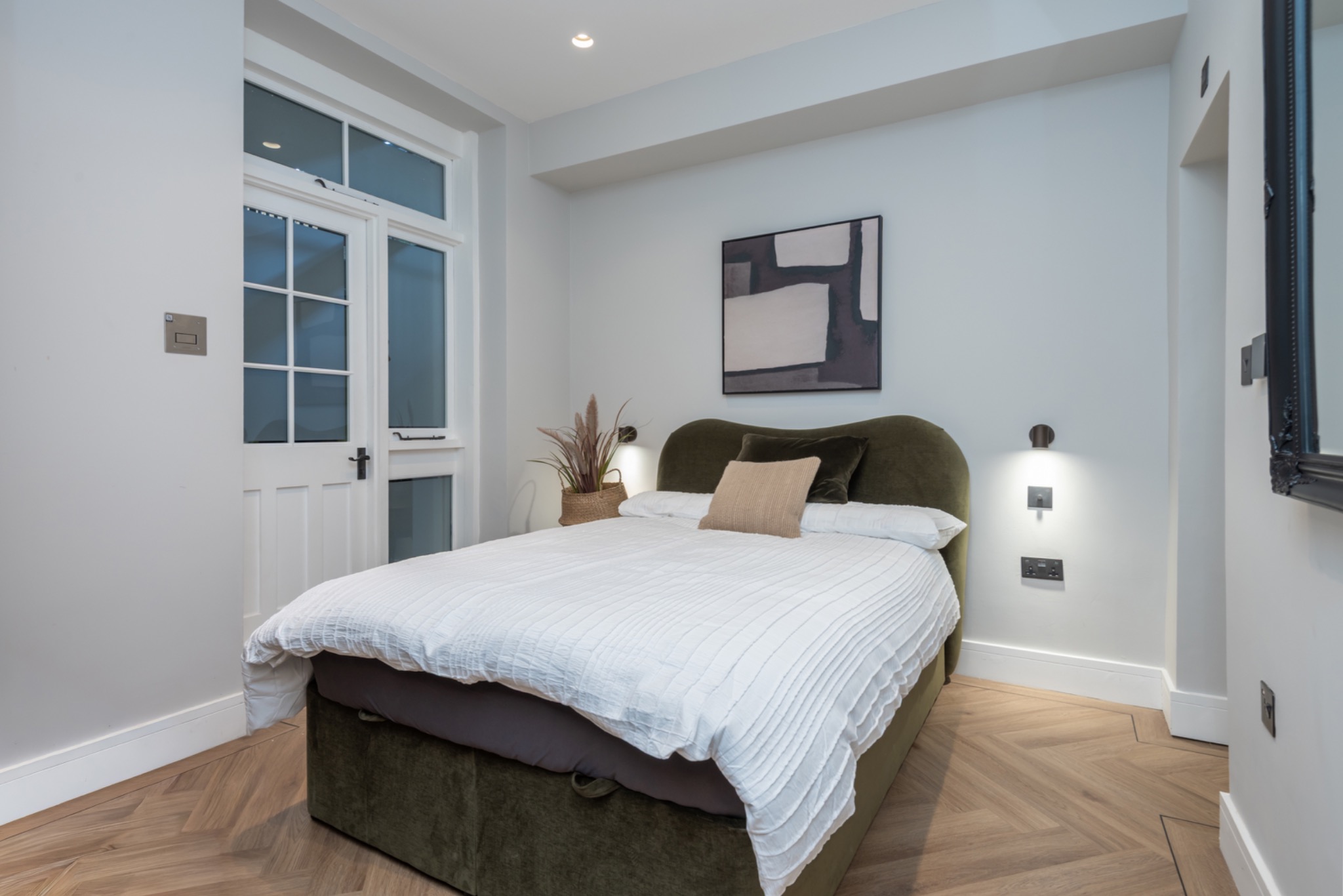 Portobello Road bedroom with olive velvet bed and herringbone flooring